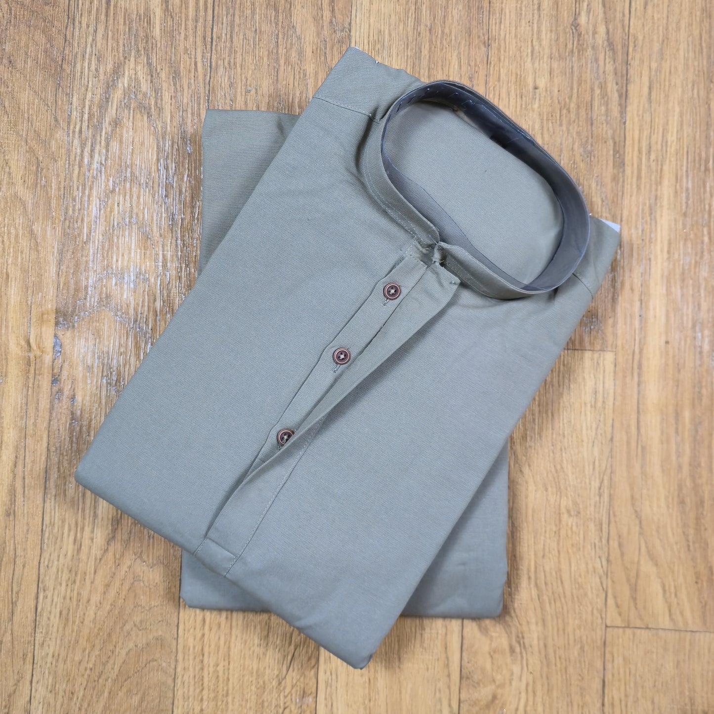 Folded gray kurta on a wooden surface