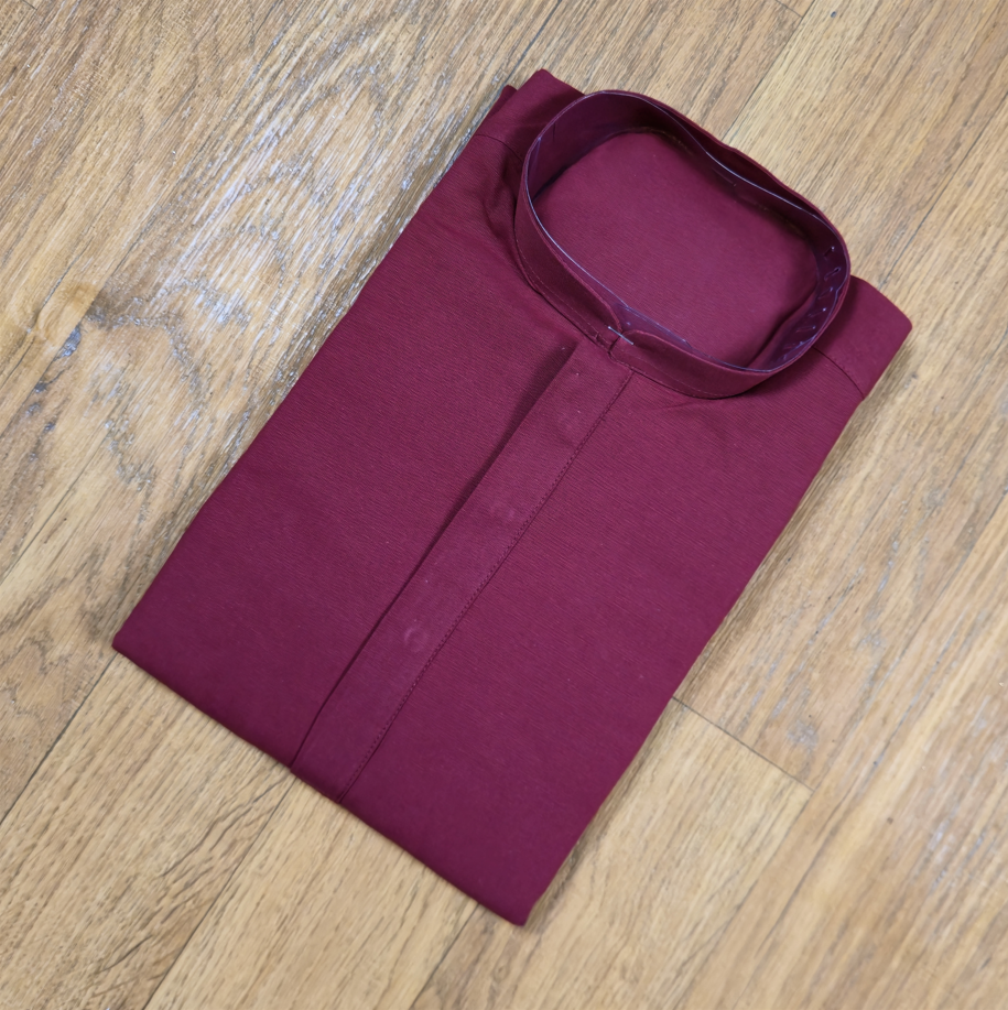 Folded maroon mandarin collar shirt on wooden floor
