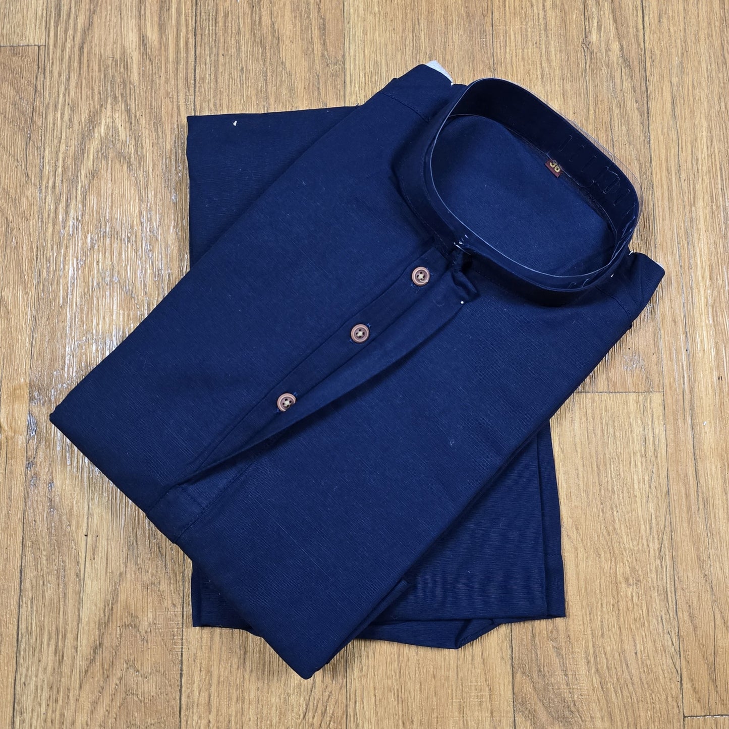 Folded Navy Blue mandarin collar Kurta on wooden floor