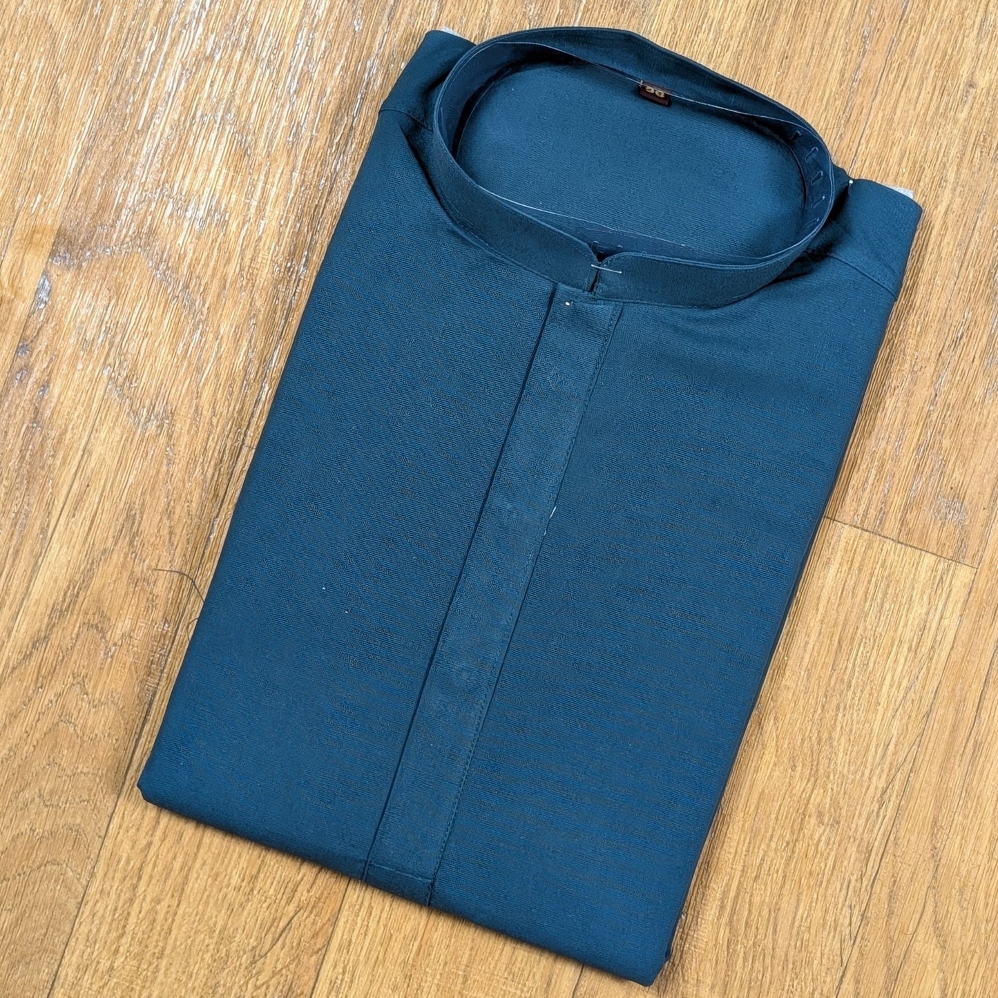 Folded Ocean Blue mandarin collar kurtawith brown buttons on wooden floor