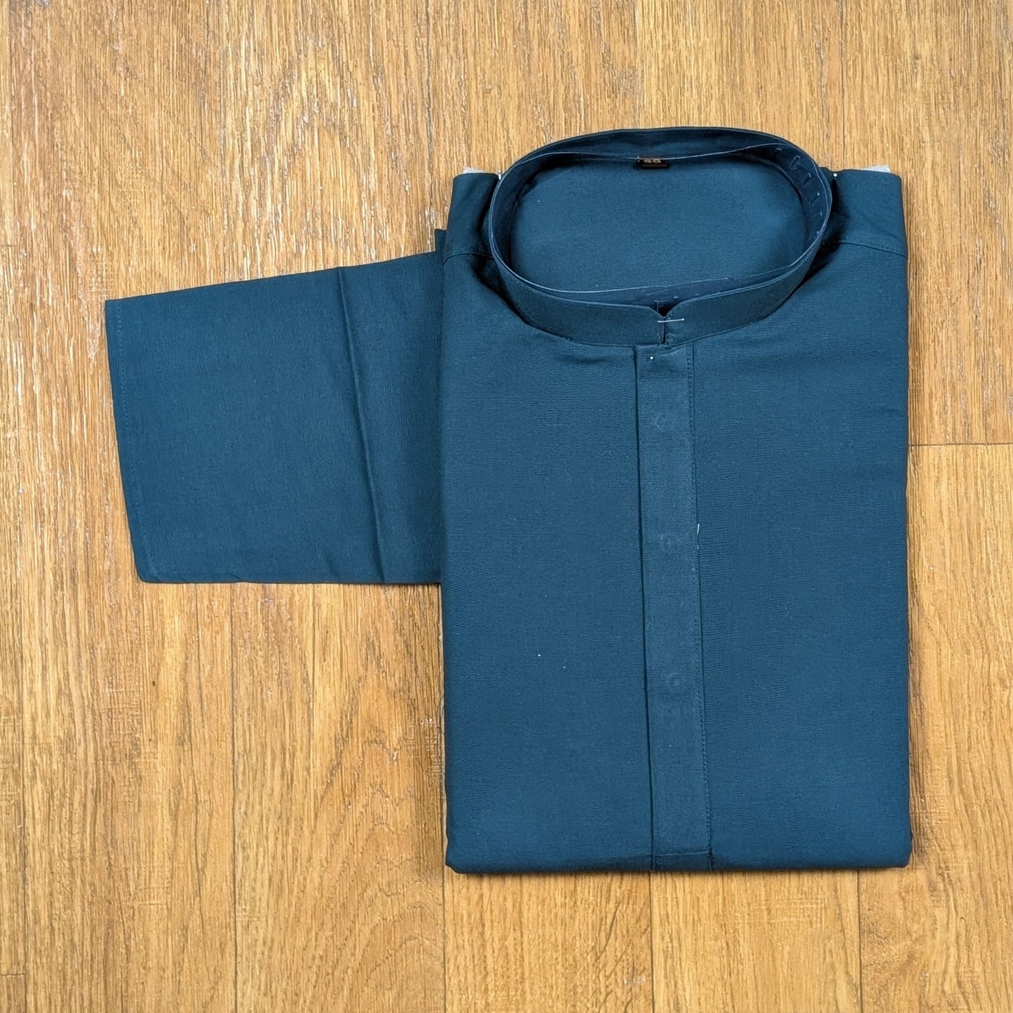 Folded Ocean Blue mandarin collar kurtawith brown buttons on wooden floor