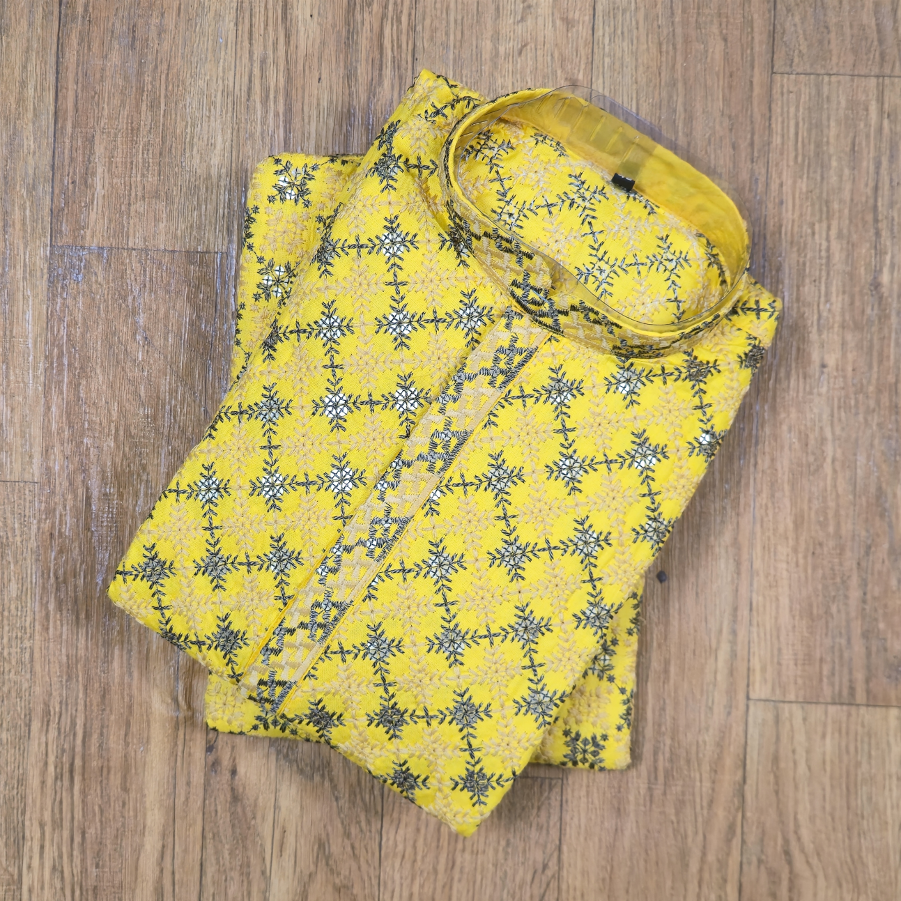 Yellow fabric with black floral pattern on a wooden surface