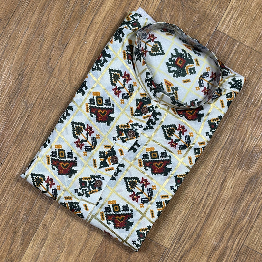Folded mandarin collar shirt with green, red, and yellow geometric floral print on white fabric, placed on wooden floor