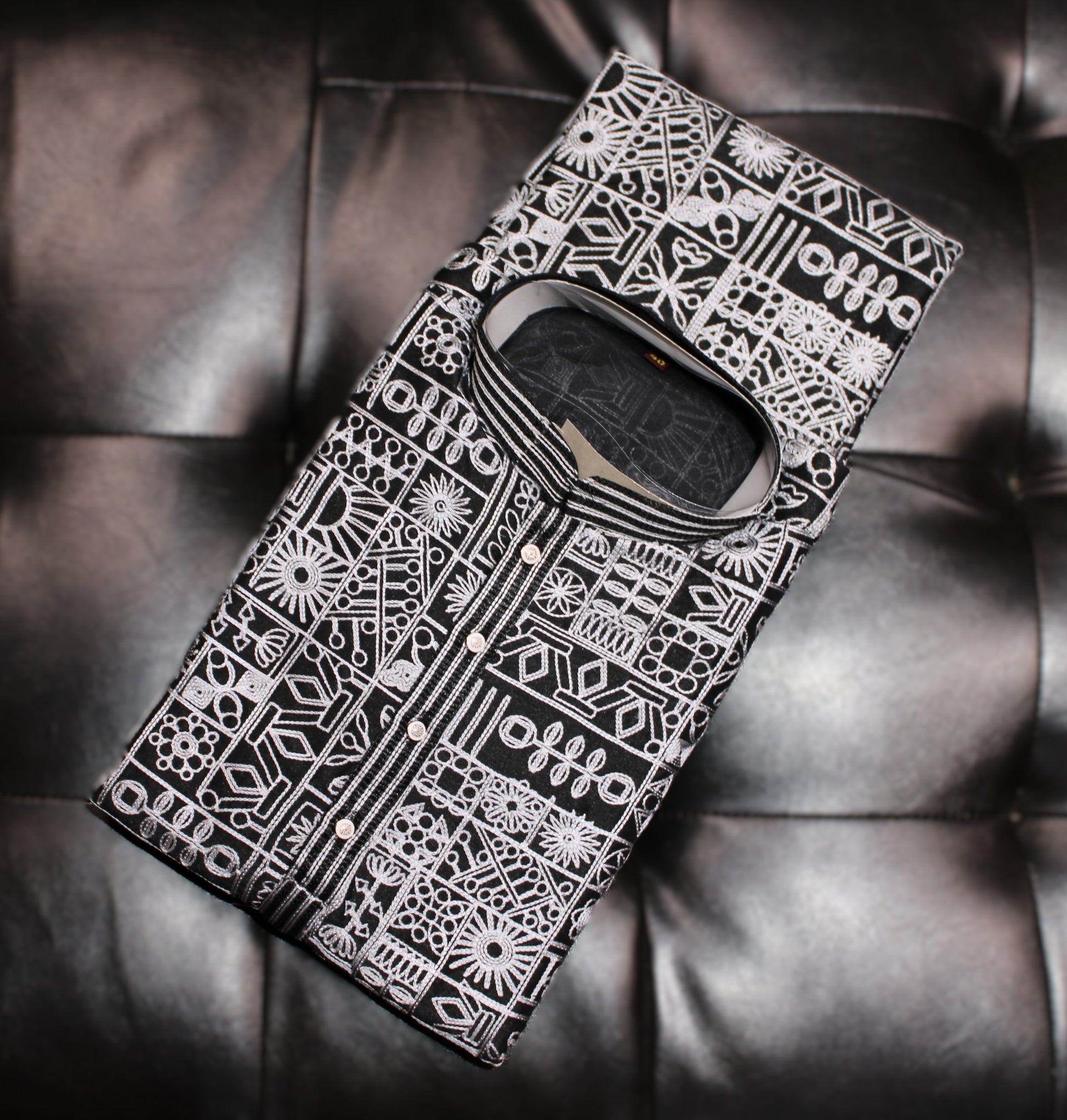 Phone case with intricate black and white pattern on a dark leather surface