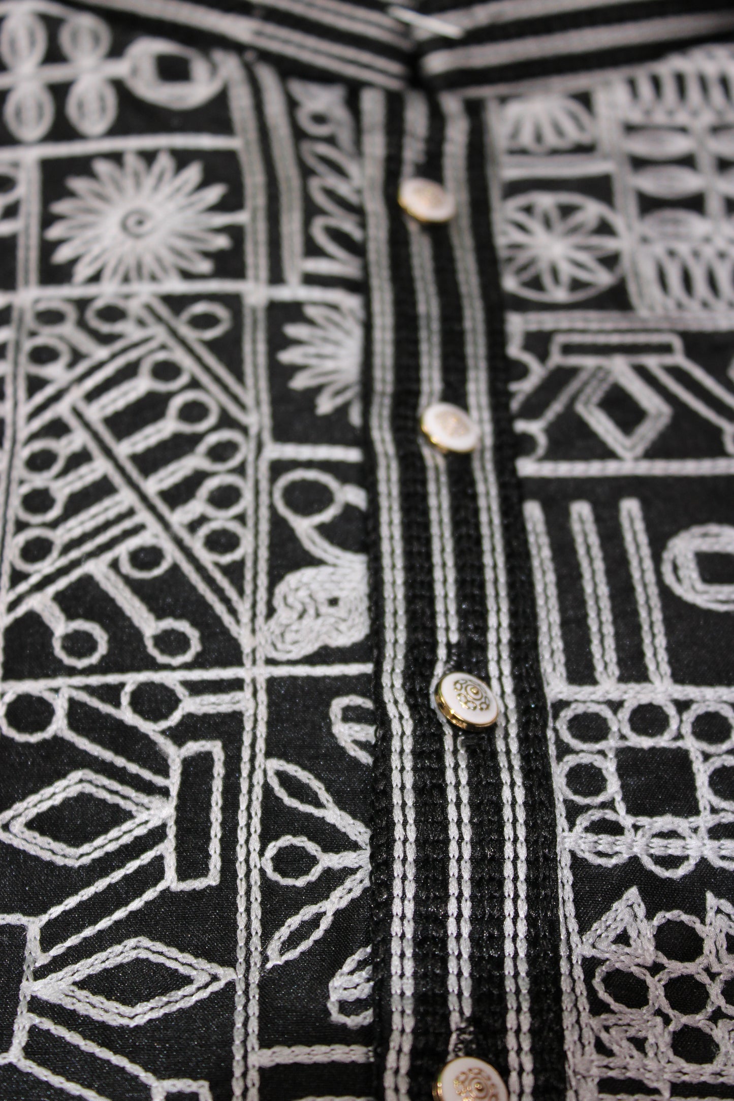 Close-up of black fabric with white geometric patterns and button details.