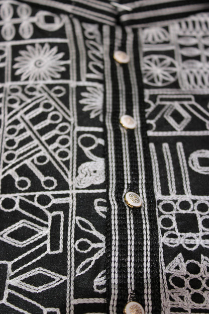 Close-up of black fabric with white geometric patterns and button details.