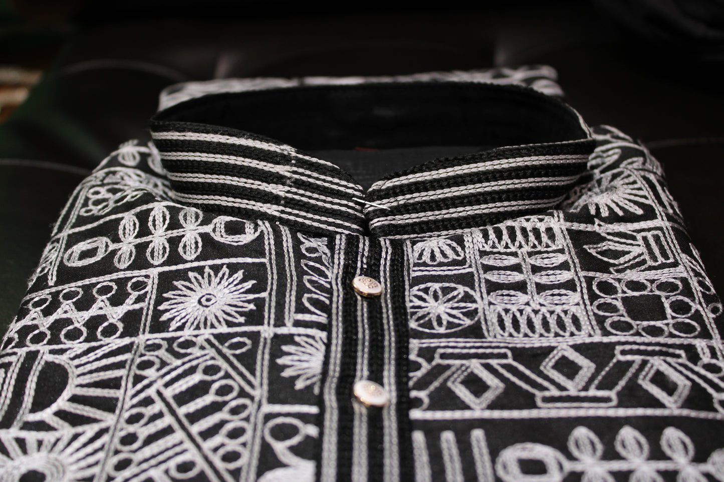 Black fabric with white embroidery patterns on a dark background