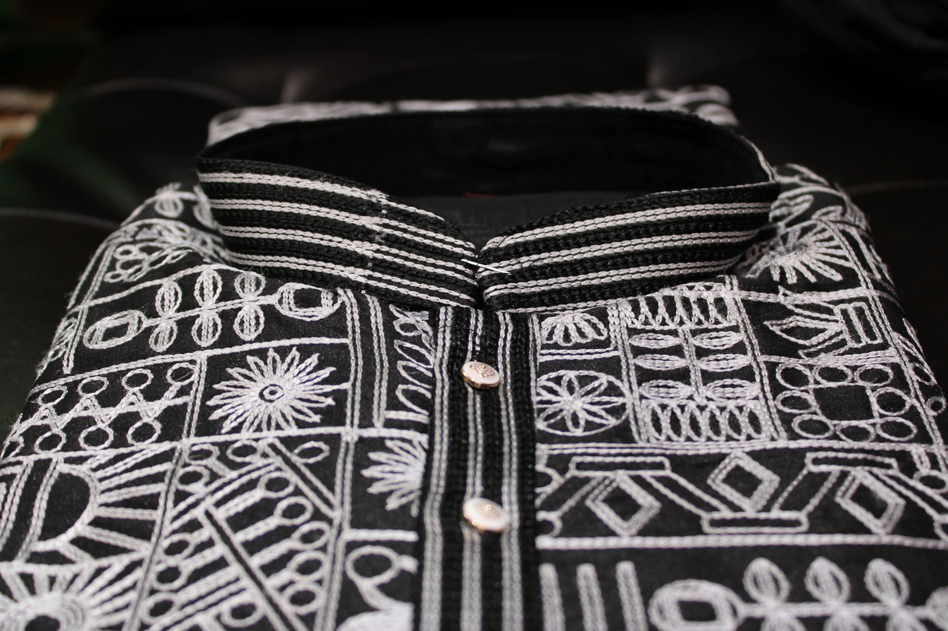 Black fabric with white embroidery patterns on a dark background