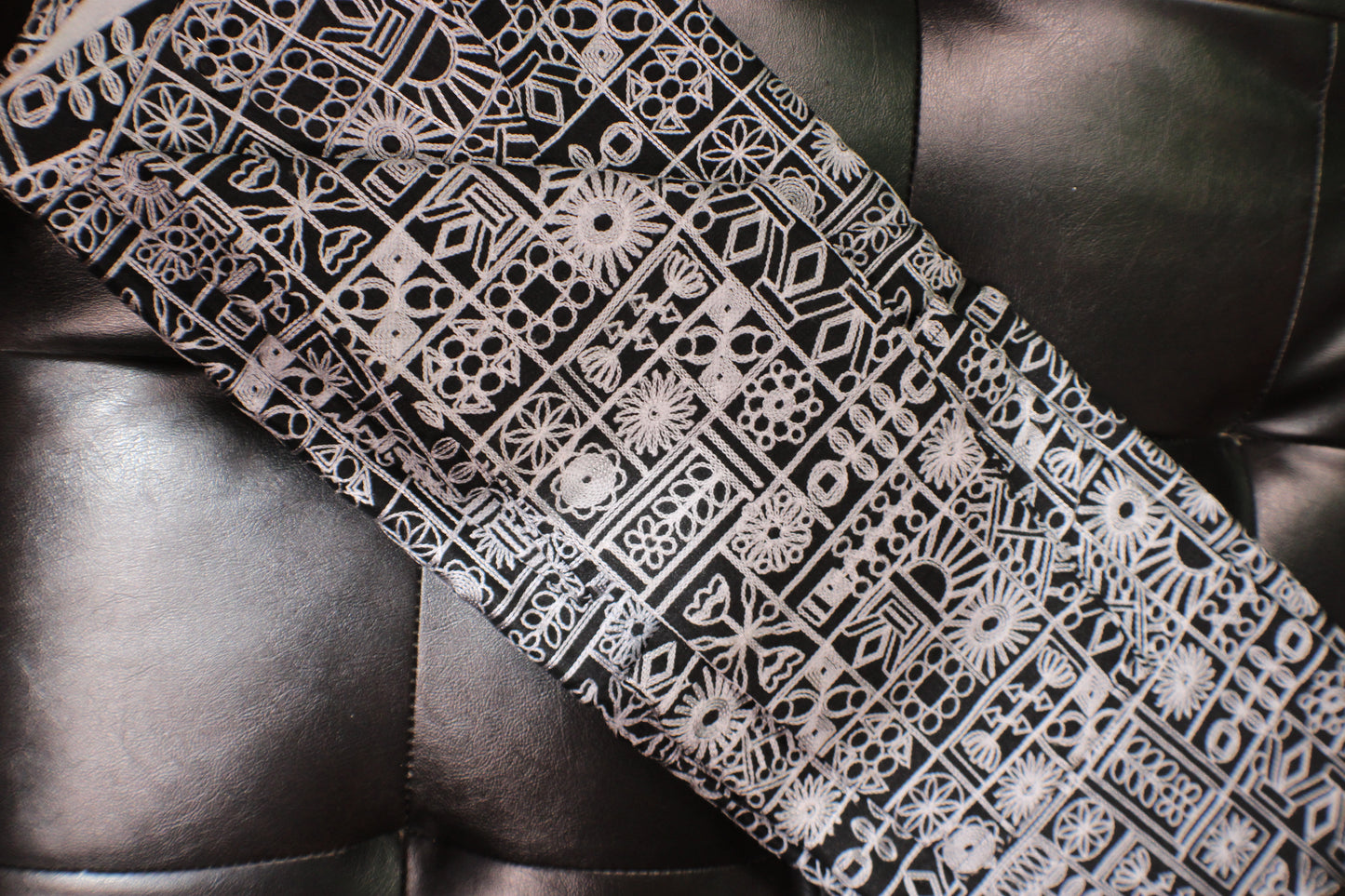 Black and white patterned tie on a dark leather surface