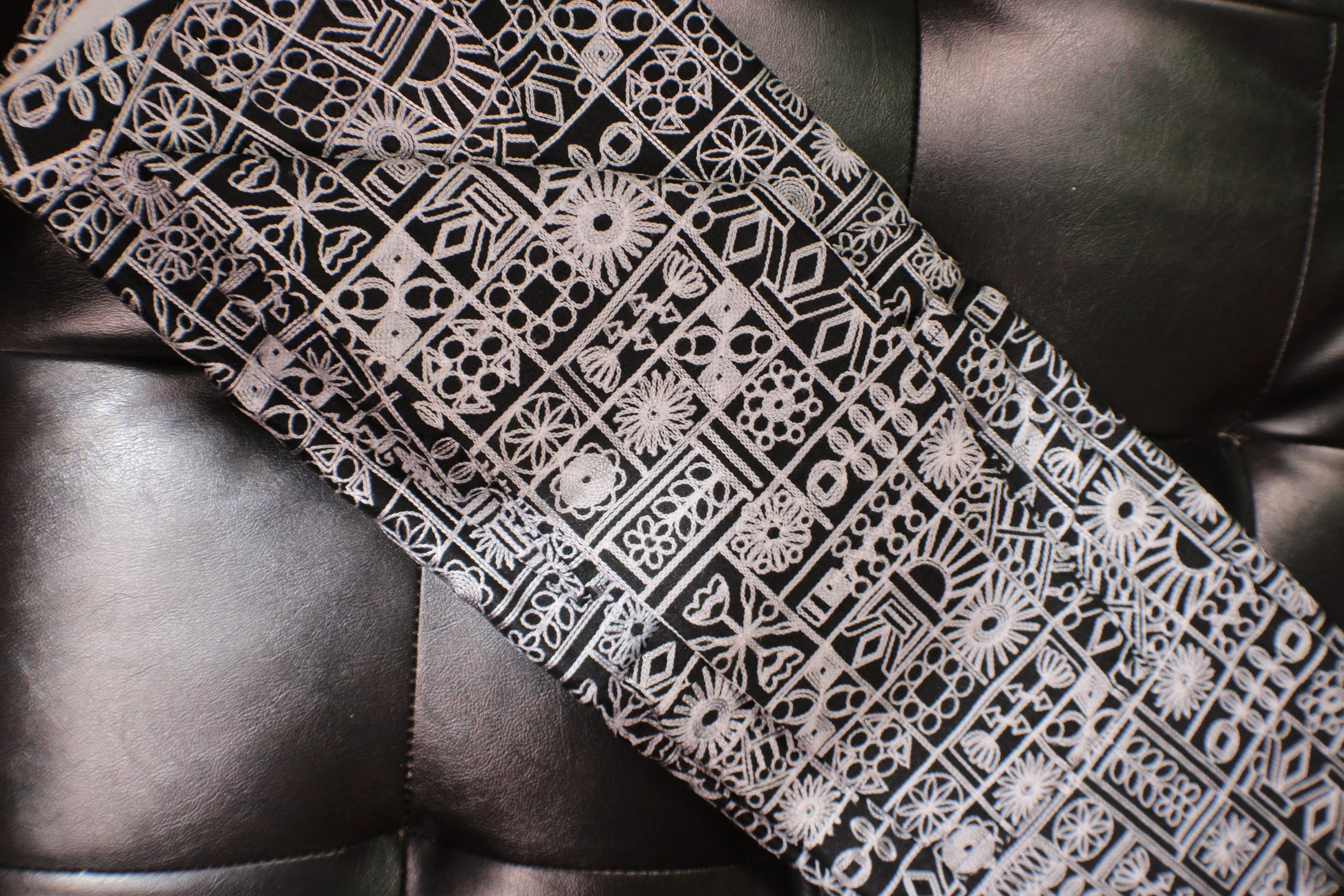 Black and white patterned tie on a dark leather surface