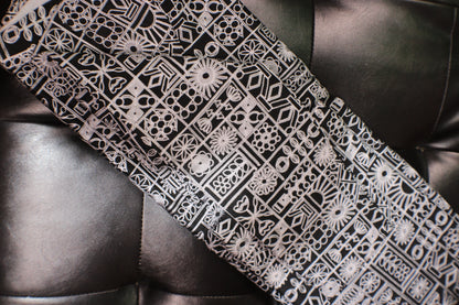 Black and white patterned tie on a dark leather surface