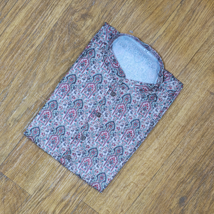 Folded mandarin collar shirt with intricate floral and paisley pattern in pink, green, and white on wooden floor