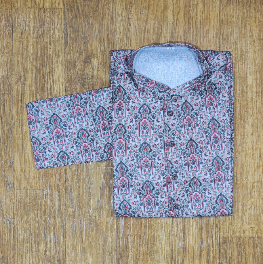 Folded mandarin collar shirt with intricate floral and paisley pattern in pink, green, and white on wooden floor