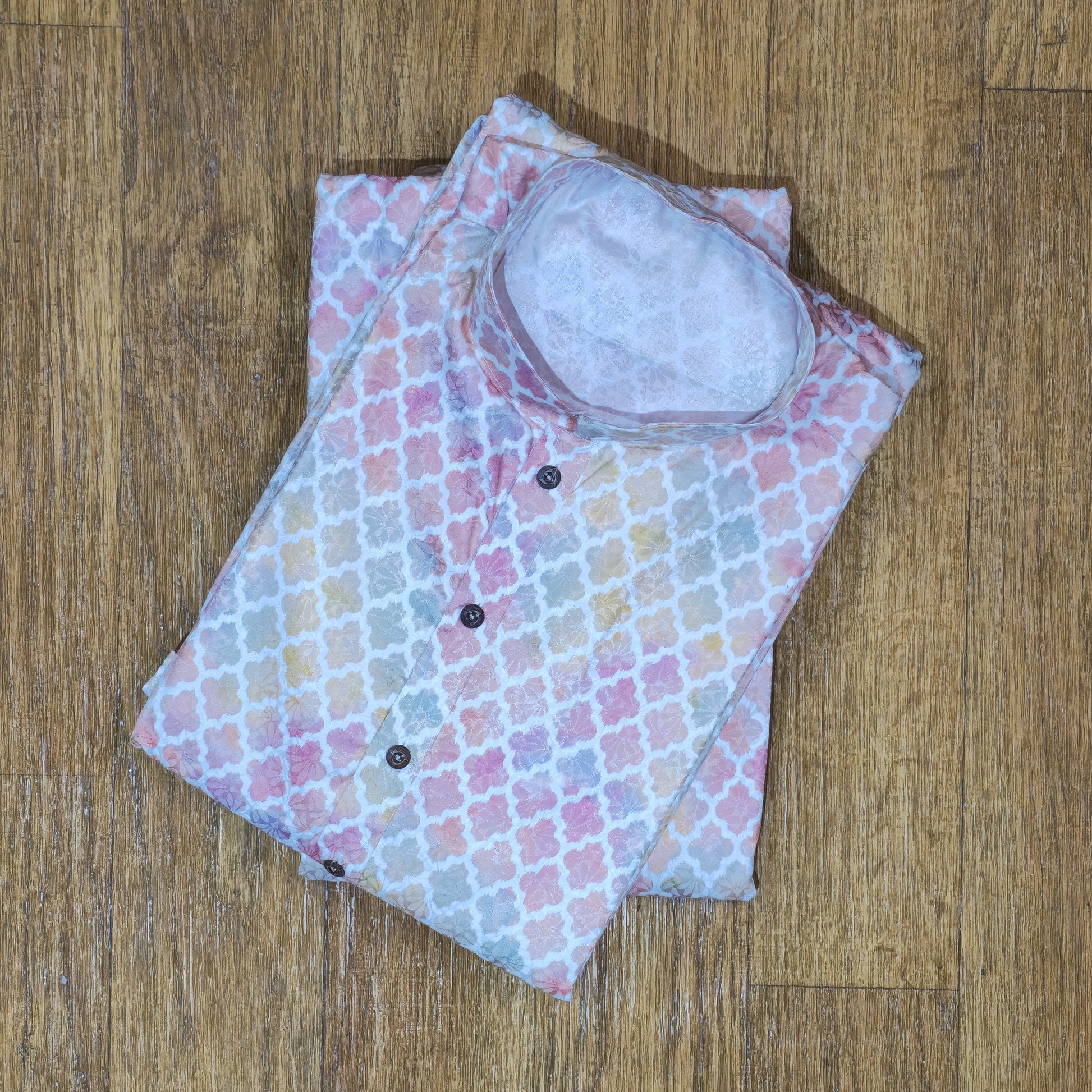 Folded baby outfit with pastel floral pattern on a wooden surface