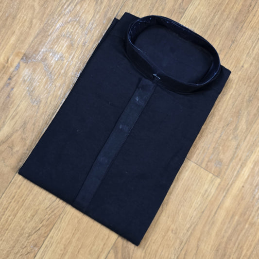 Folded black mandarin collar shirt with brown buttons on wooden floor