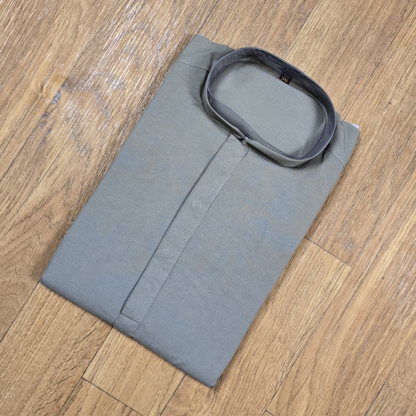Folded gray kurta on a wooden surface