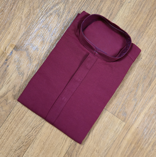 Folded maroon mandarin collar shirt on wooden floor