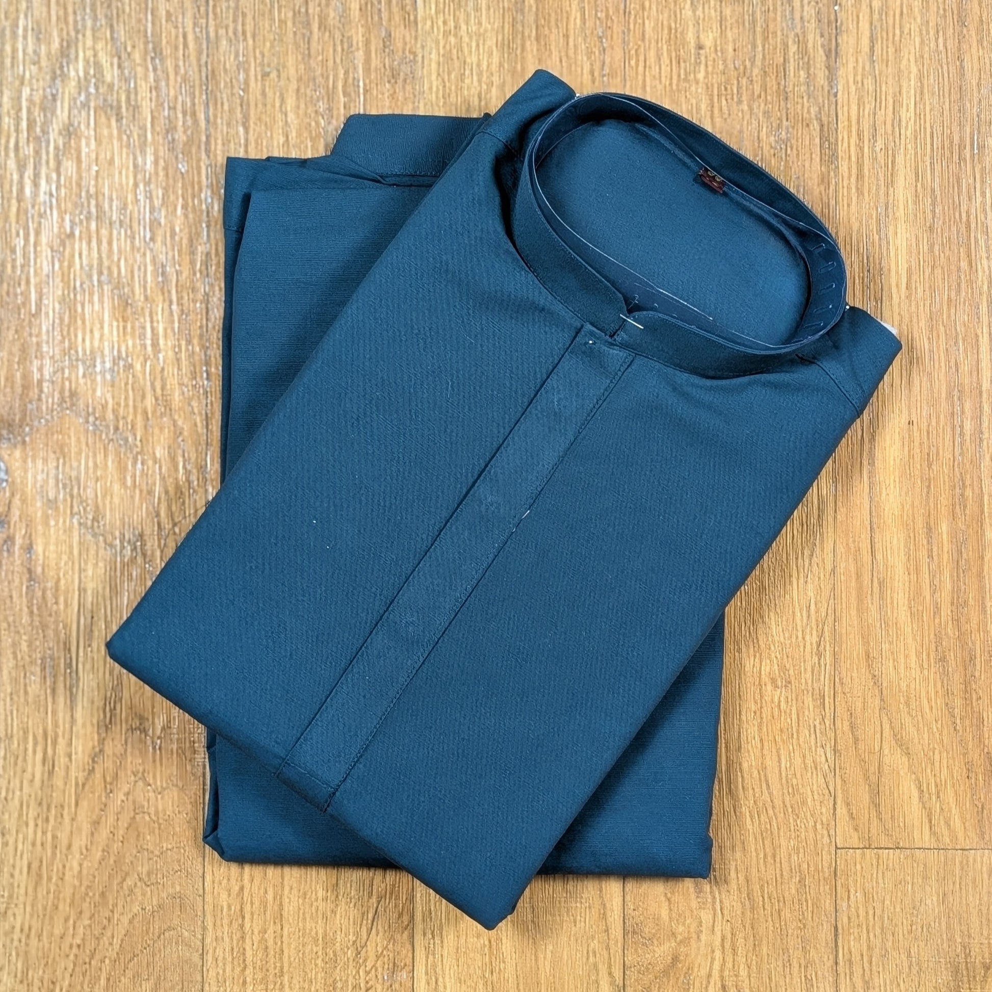 Folded Ocean Blue mandarin collar kurtawith brown buttons on wooden floor