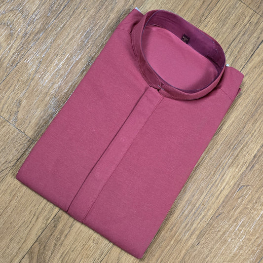 Folded dusty rose mandarin collar shirt on wooden floor