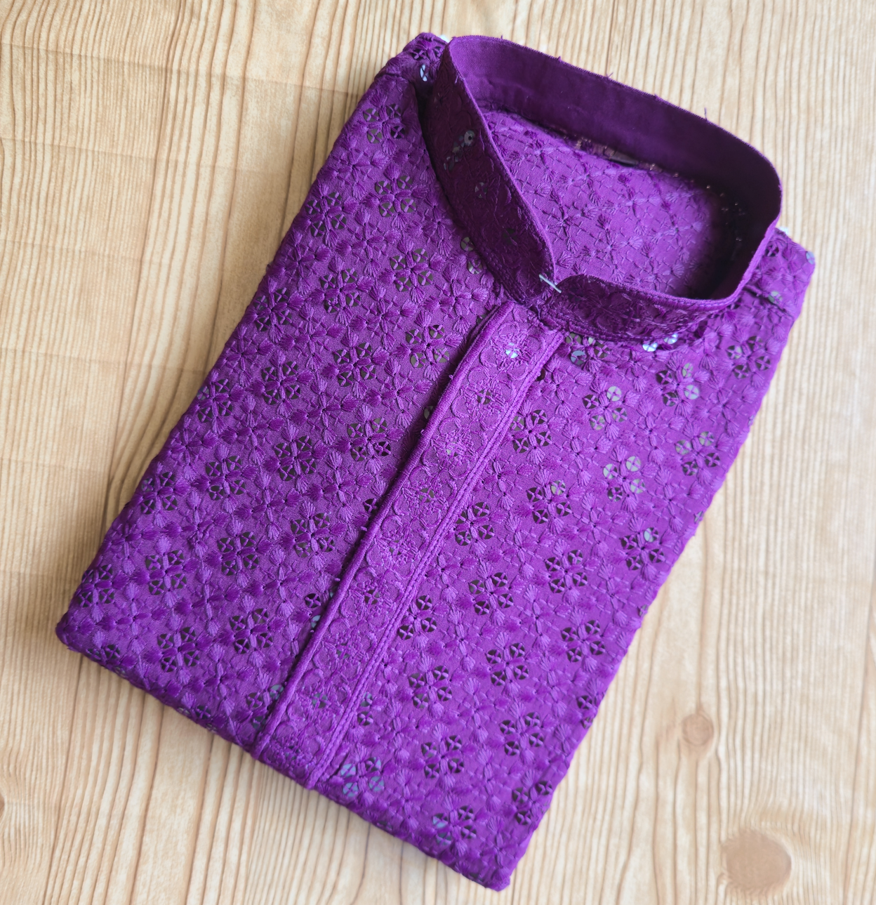 Folded purple shirt with floral pattern on a wooden surface
