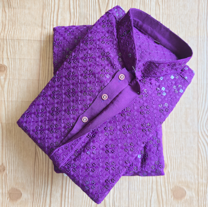 Folded purple sequin shirt on a wooden surface