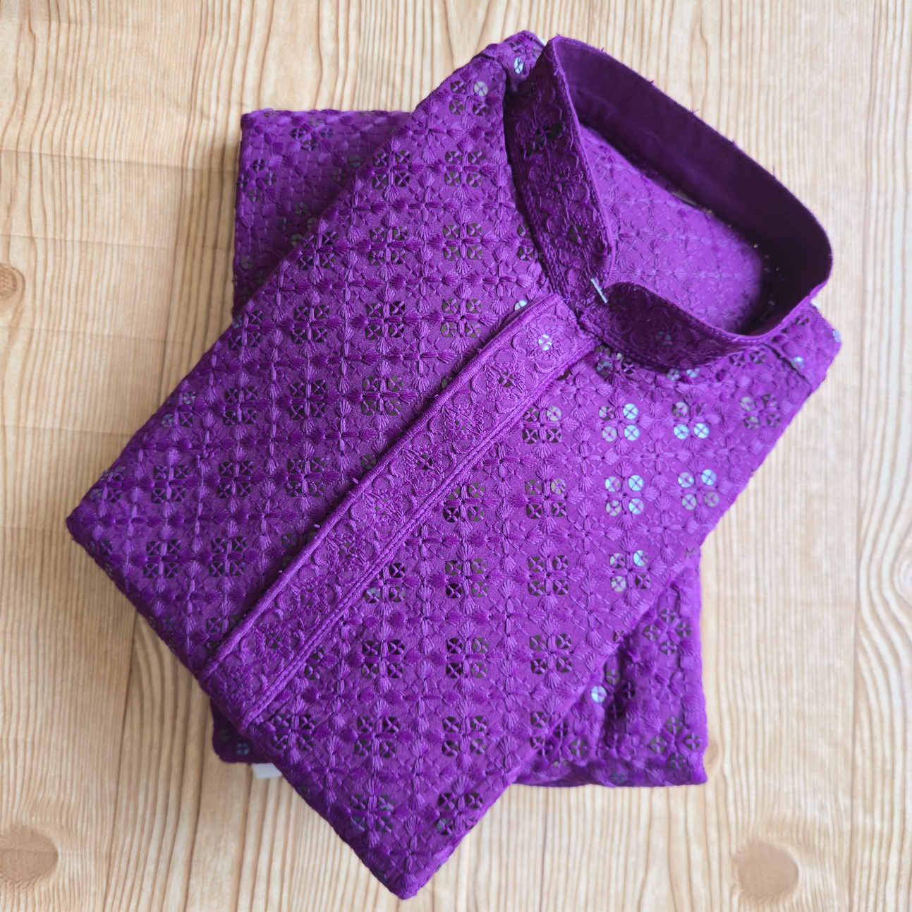 Folded purple garment with intricate patterns on a wooden surface