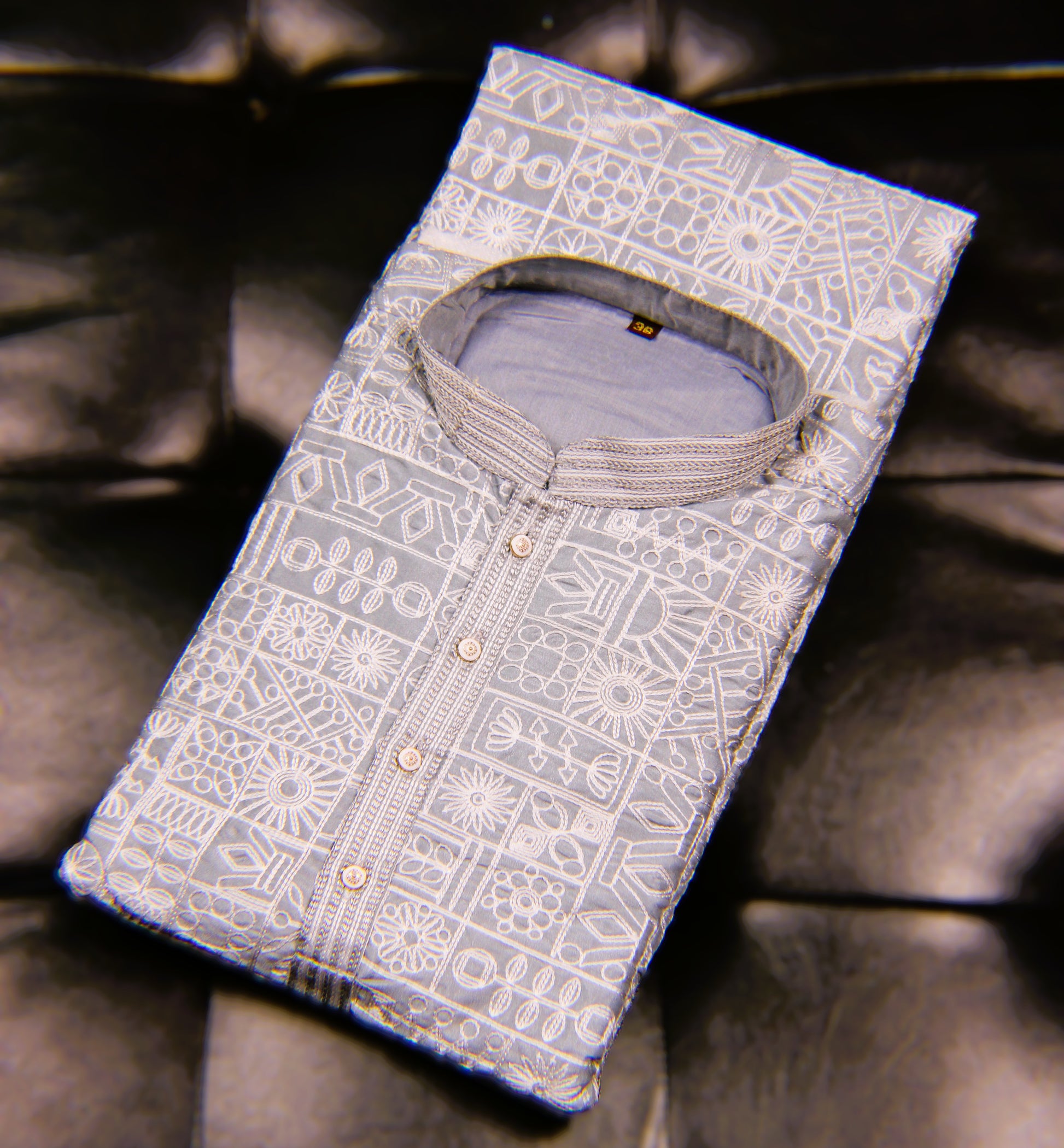 Folded shirt with intricate patterns on a dark fabric background